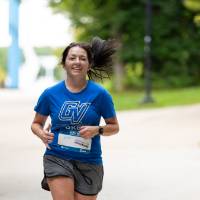 Participant in blue shirt running through campus